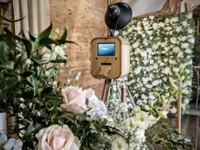 A smiling bride in a white lace dress interacts with a circular selfie station at an outdoor night-time event. Surrounding greenery and soft lighting create a warm atmosphere, perfect for those considering luxury photo booth hire in Oxfordshire